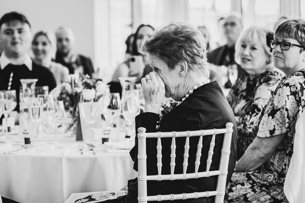 an elderly lady wipes away a tear during the speeches