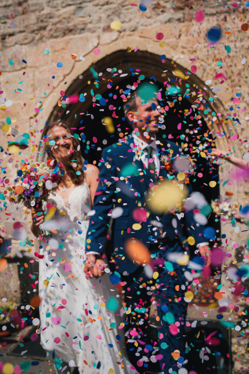 confetti showers around a couple who exit a church