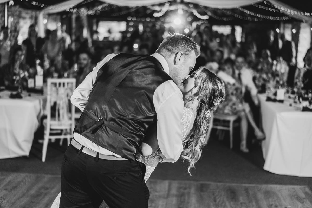 a couple lean back and kiss as people watch them from behind