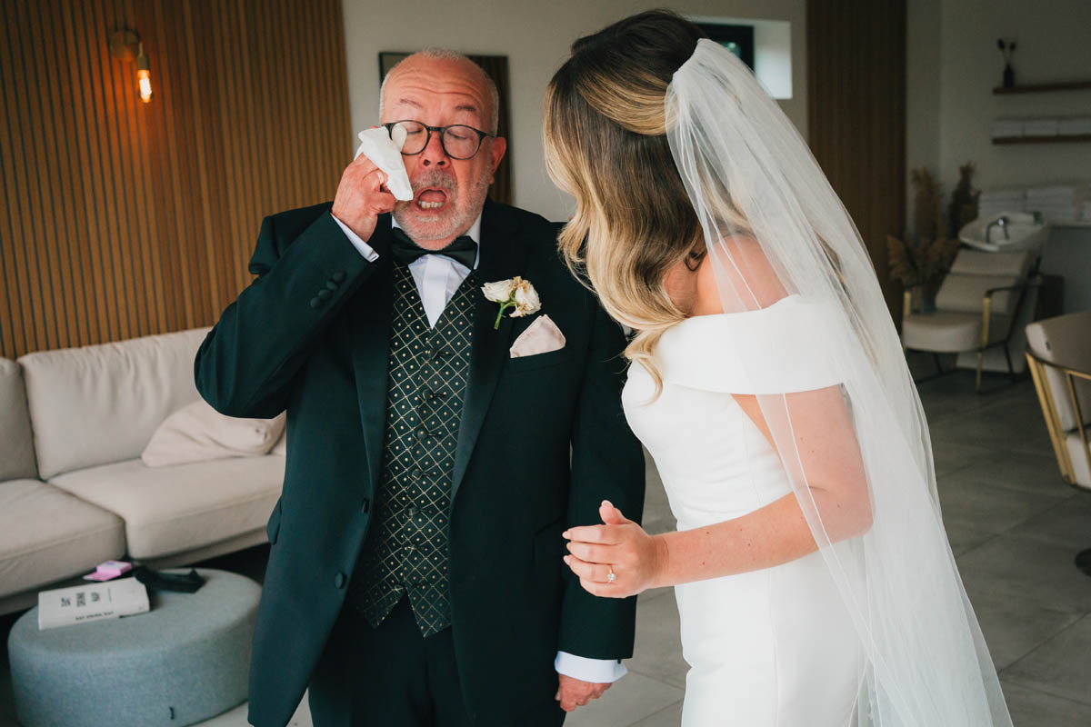 a man wipes away a tear fro underneath his glasses