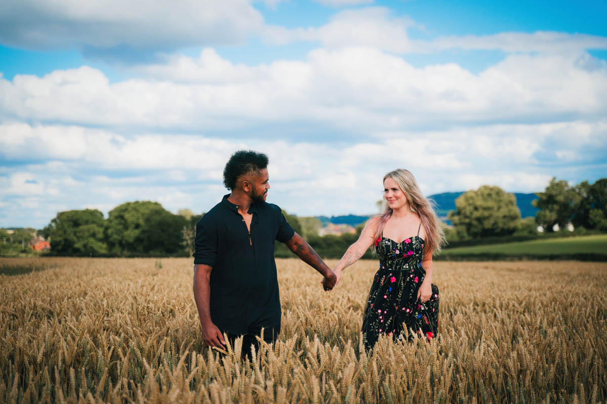 a woman leads her partner through a field of corn