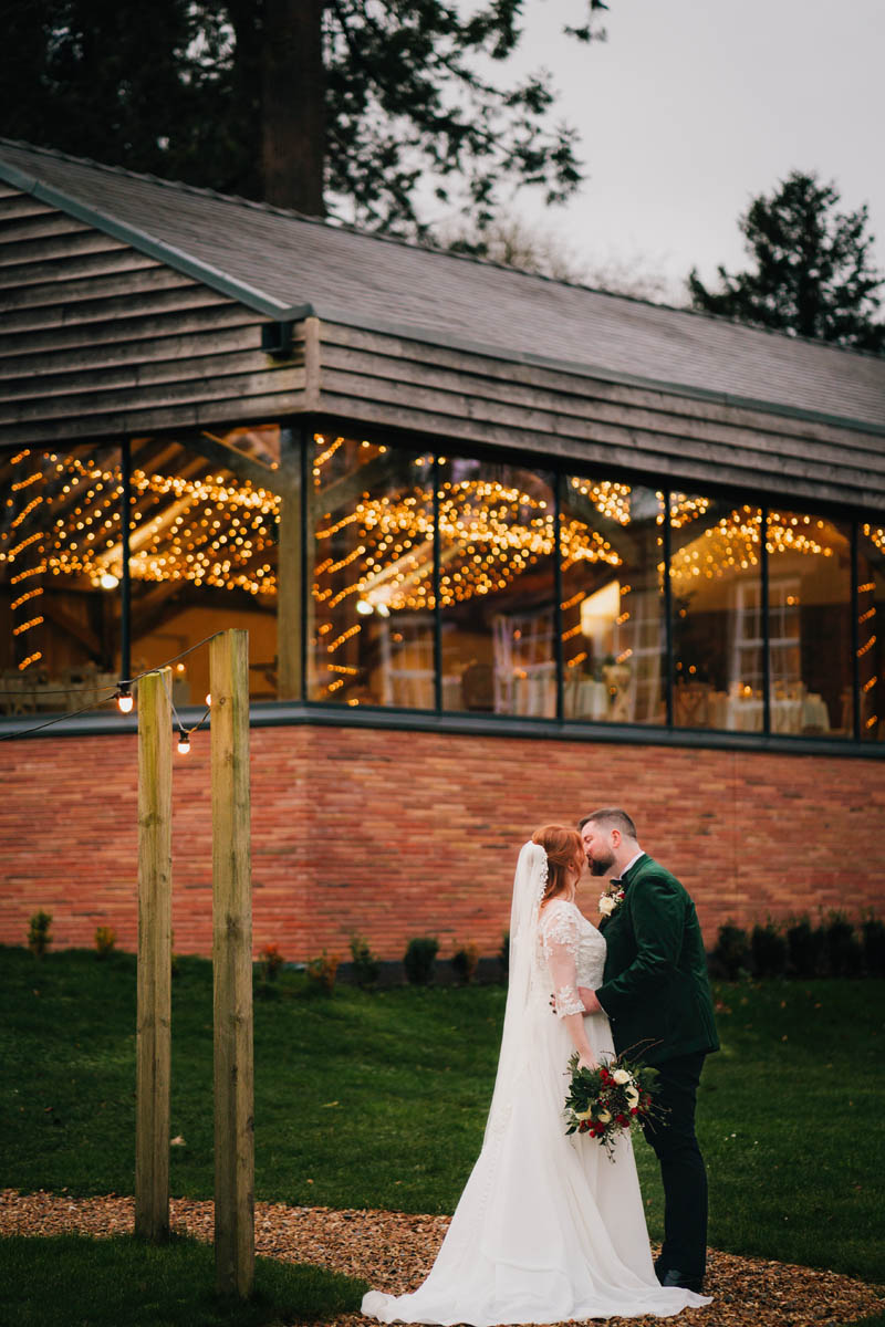 a newly-married couple kiss in front of bredenbury court barns