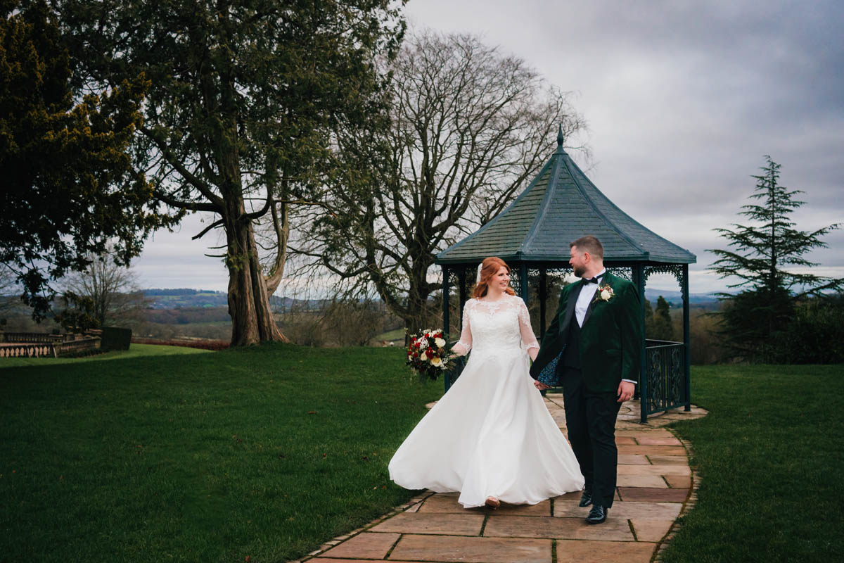 a bride and groom walk hand in hand at Bredenbury court barns