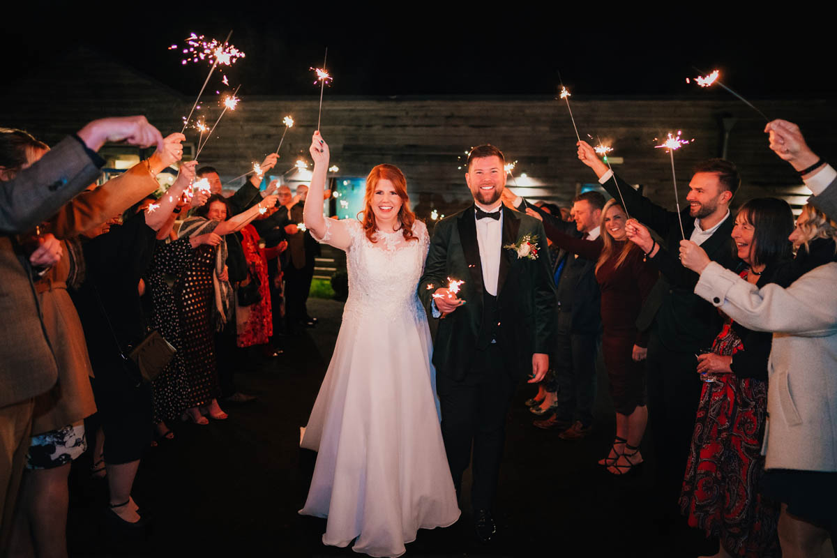 a couple wave sparklers during their sparkler exit