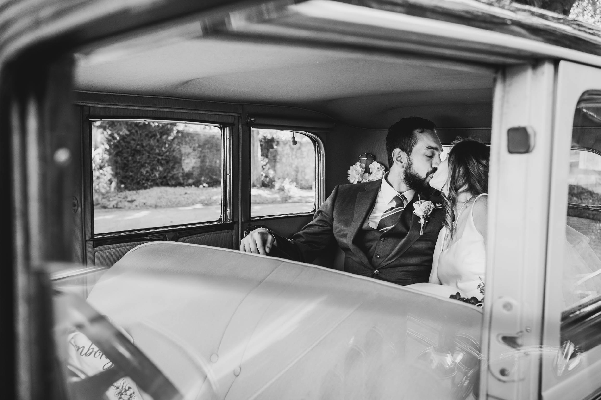 a couple kiss in their wedding car on Bristol's city streets