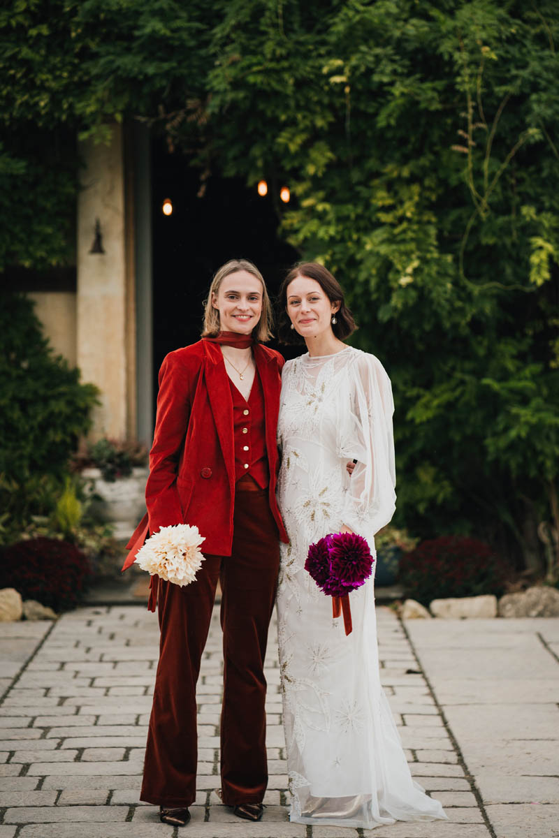 two brides pose in front of the camera outside their cotswolds wedding venue