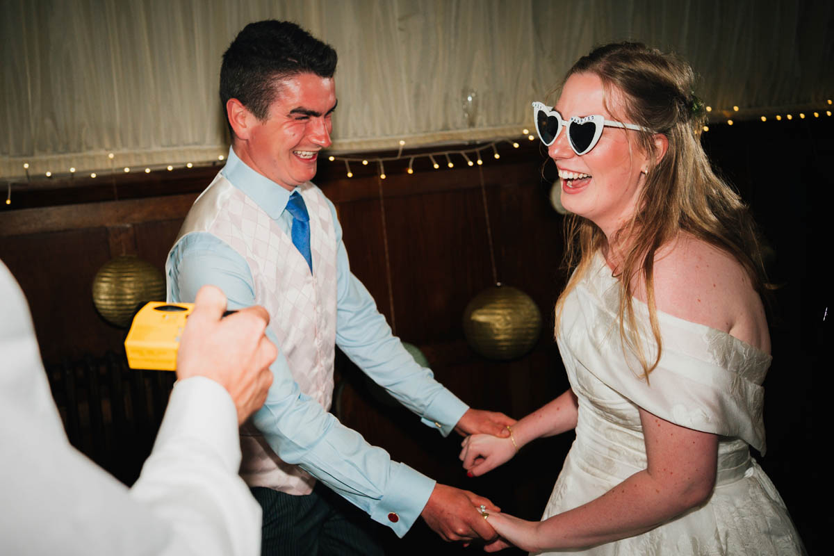 a bride and wedding guests hold hands and dance