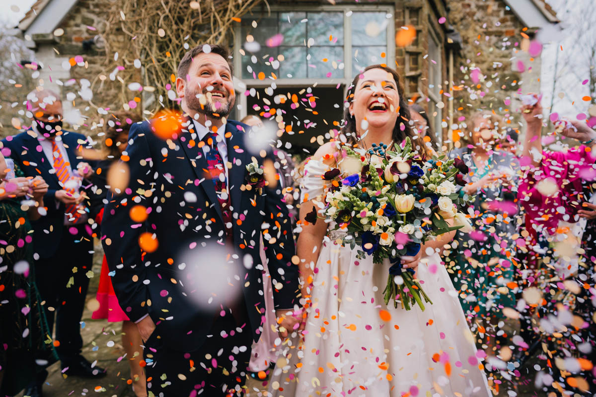 guests throw confetti over thr bride and groom