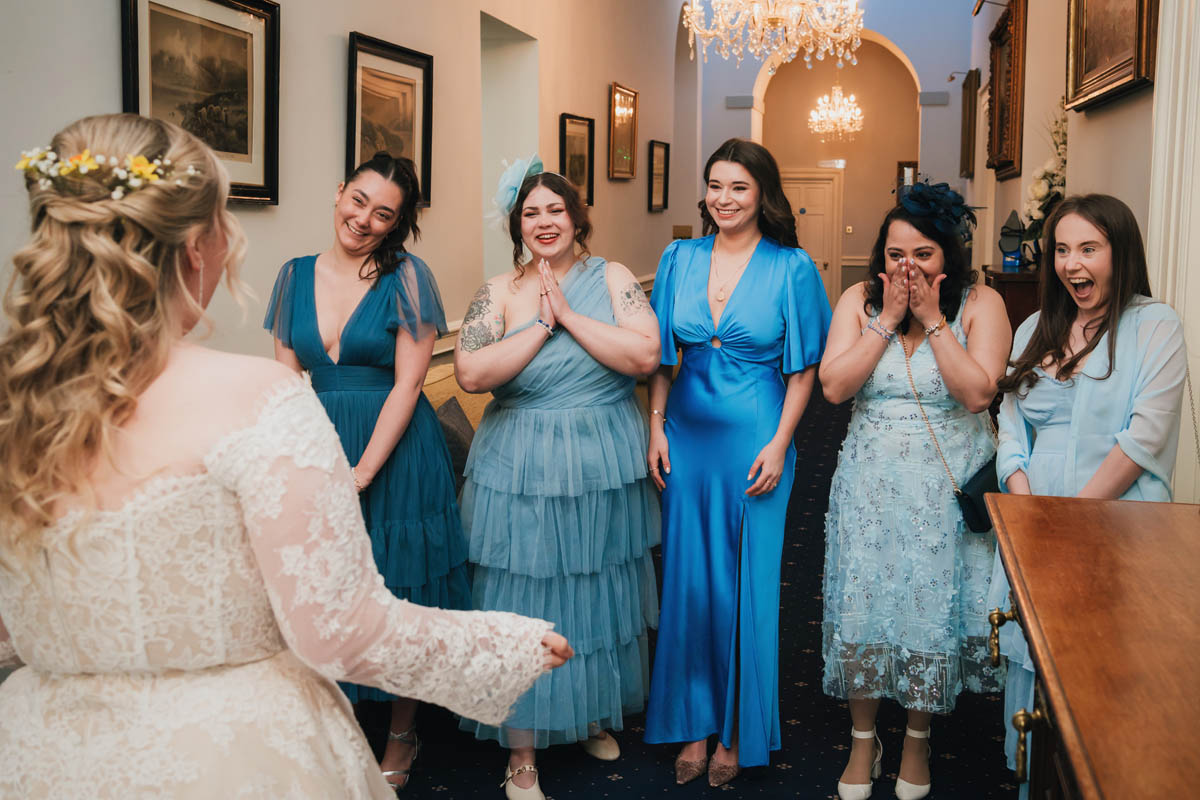 bridesmaids look joyfully at the bride