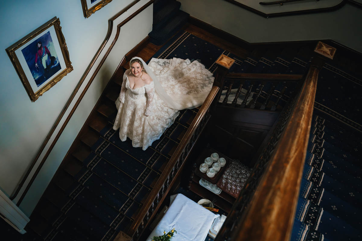 a bride walks down the grand staircase at clearwell castle
