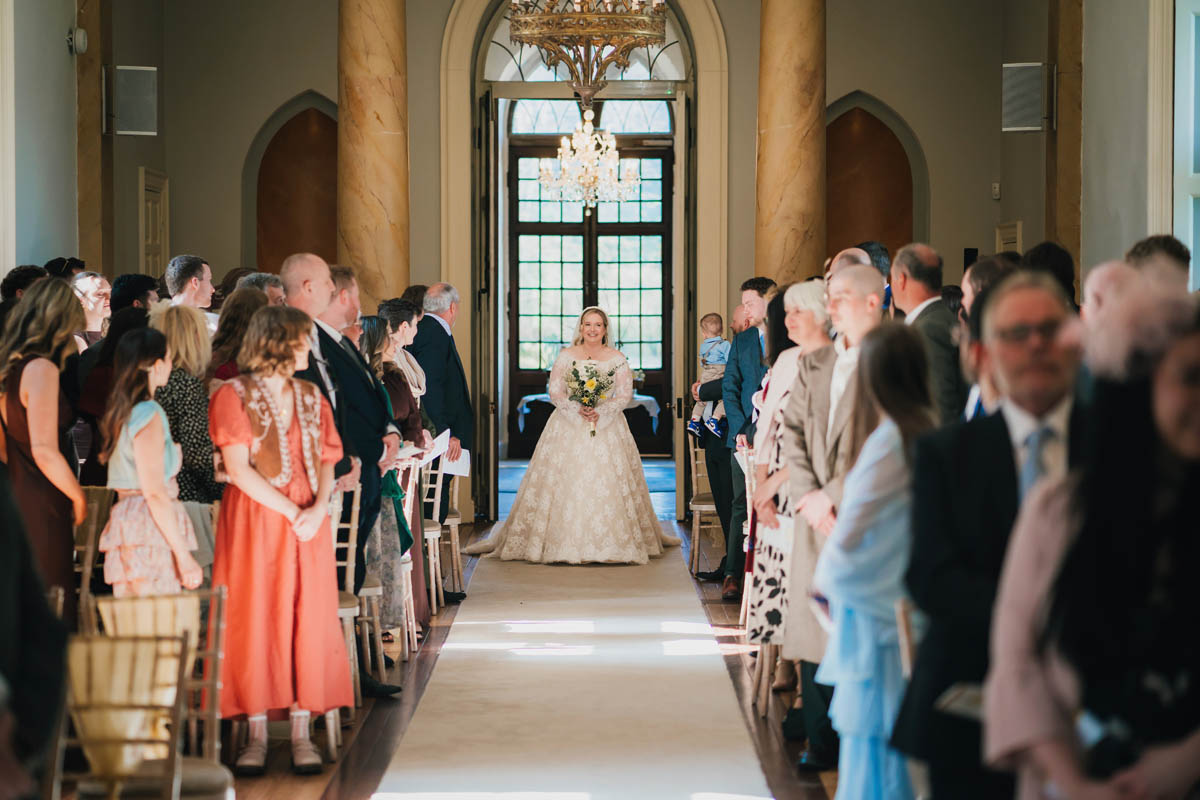 a woman in a white dress walks down the aisle