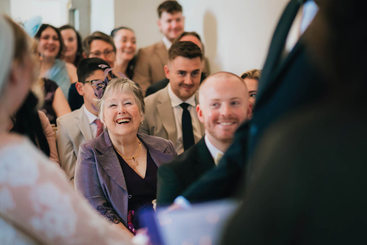 wedding guests smile as the couple say their vows