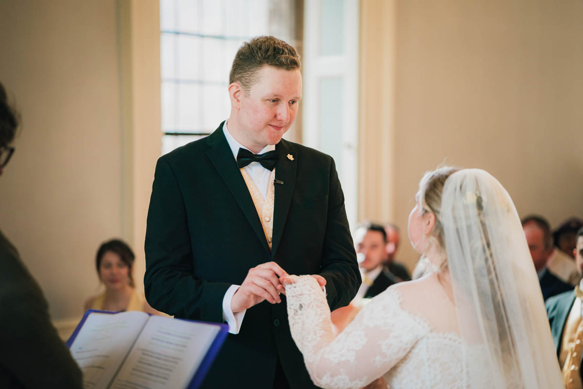 the groom looking emotional as he places the ring on his wife's finger