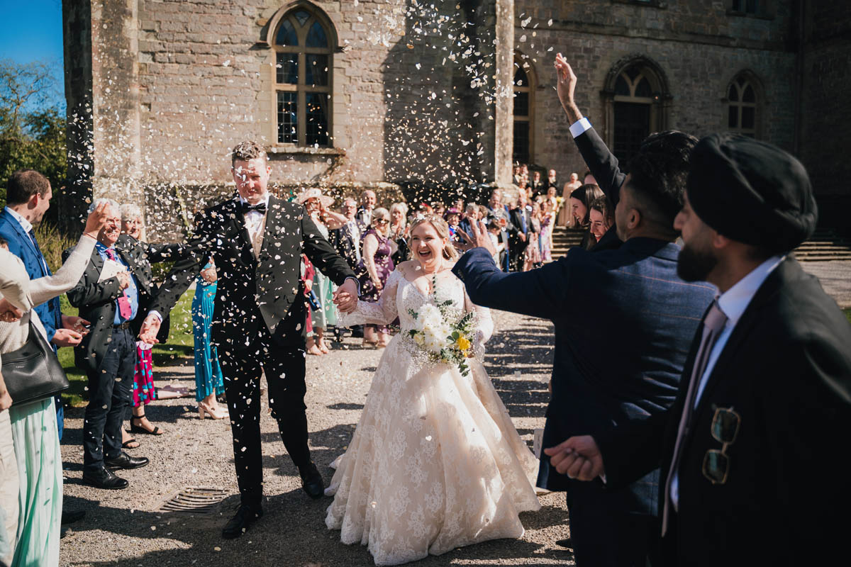 a couple smile as guests throw confetti