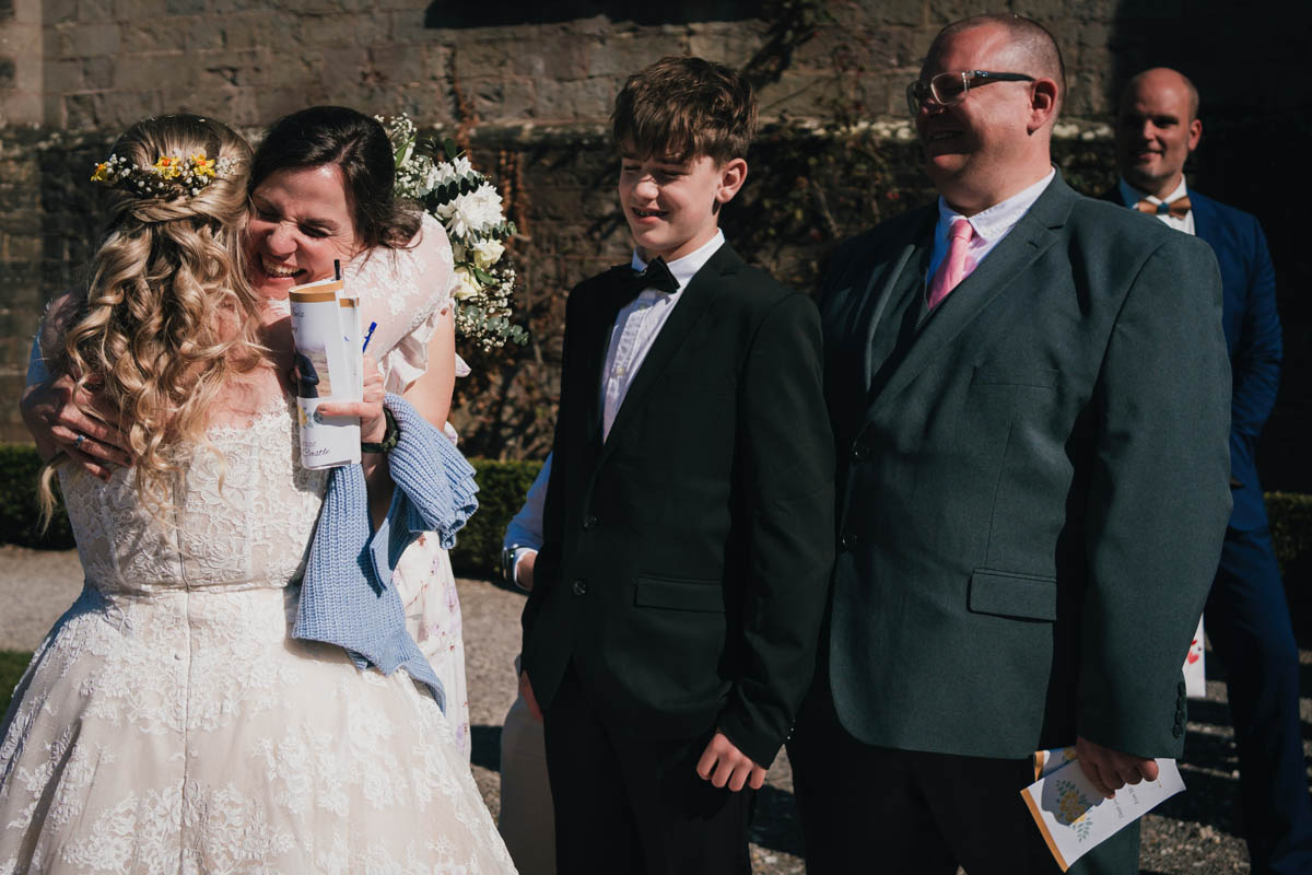 wedding guests hug the newly-married