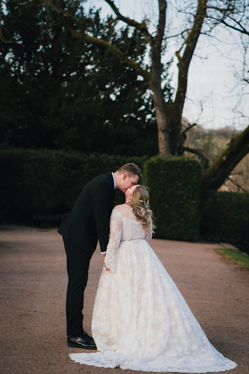 the back of a bride and groom sharing a kiss