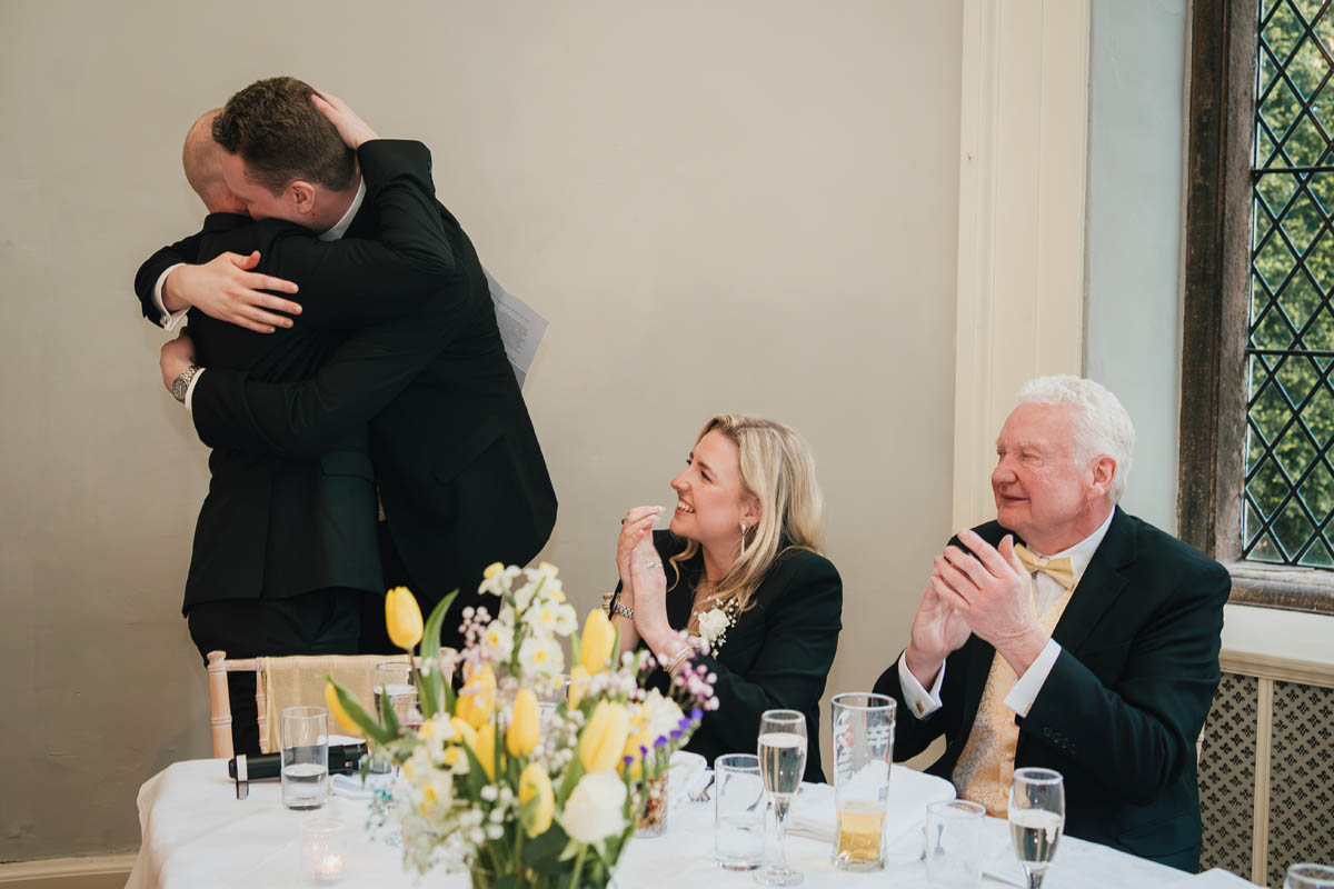 two men hug as guests clap and smile