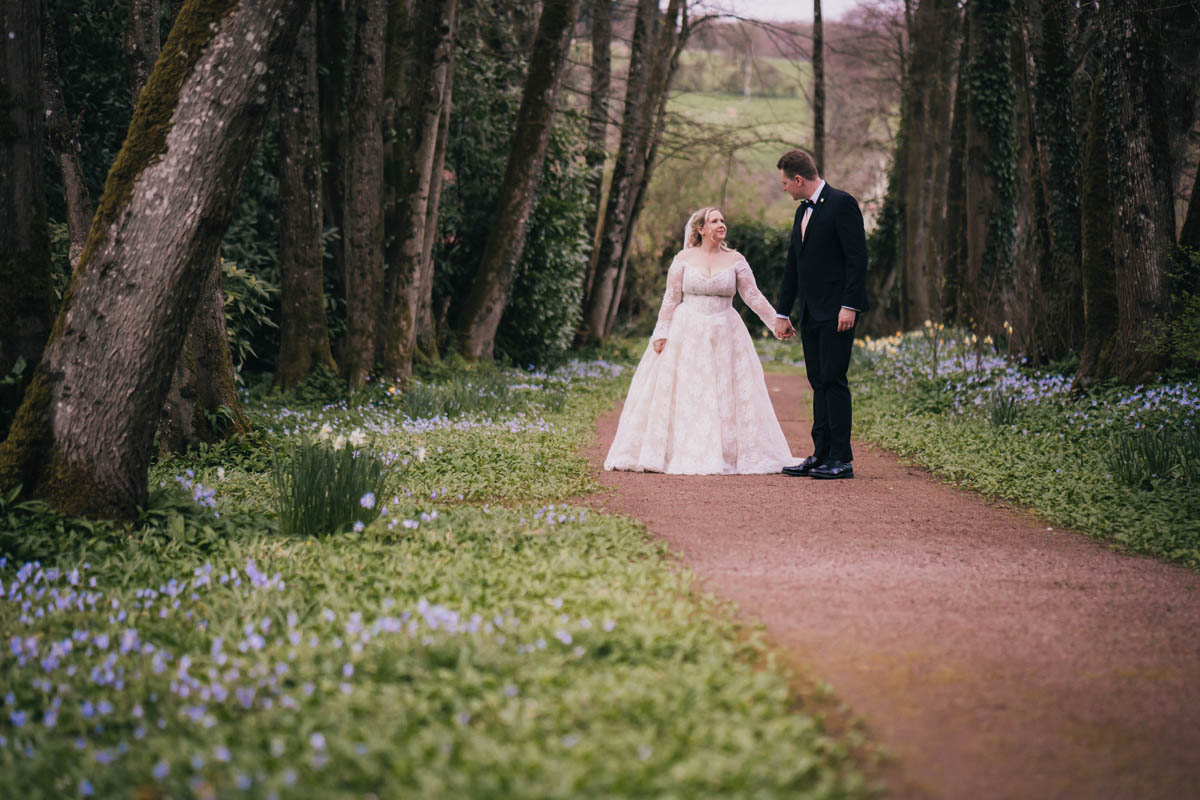a couple walk along a path surrounded by bluebells and daffodils