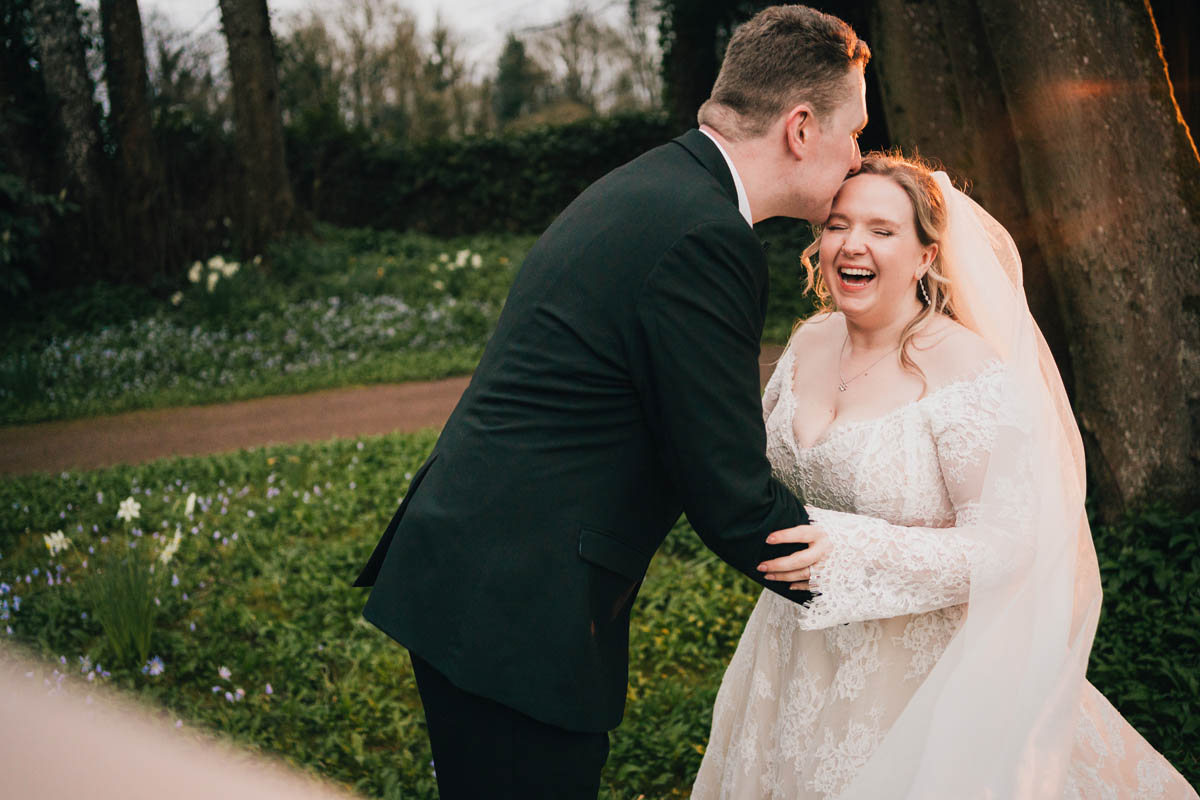 a bride laughs as her new husband kisses her forehead