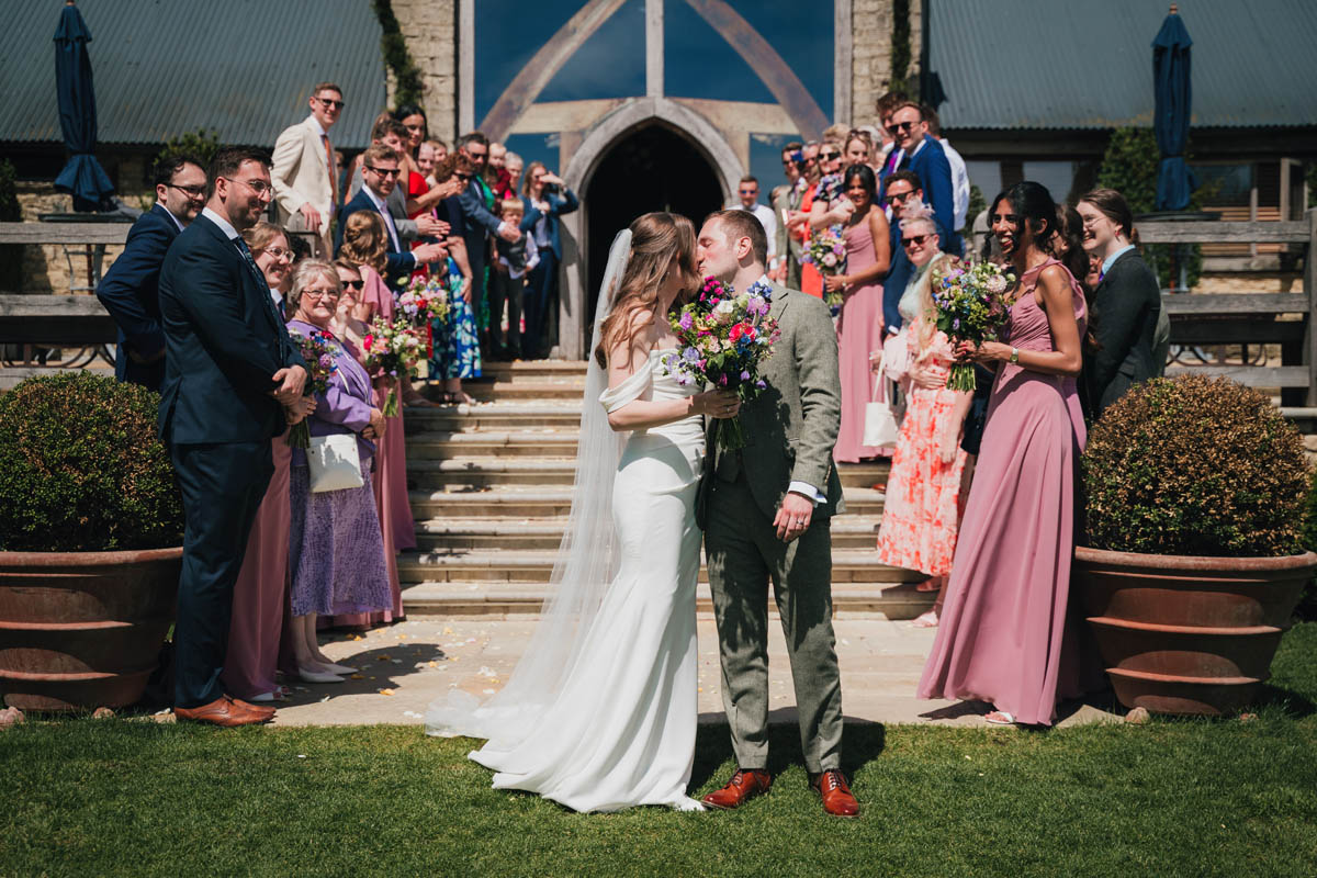 guests cheer as the newly-weds kiss outside the cotswolds venue